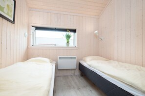 Ein kleiner Raum mit zwei Betten, einem Fenster mit Blick, einem Heizkörper und einer Wandleuchte.