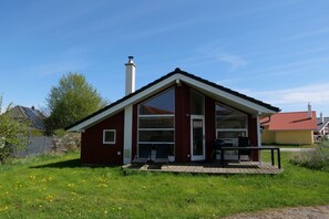 Ein rotes, eingeschossiges Haus mit einer großen Veranda und einem Schornstein.