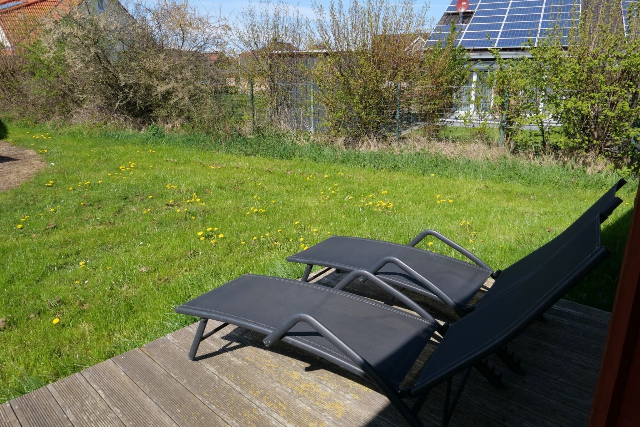 Una terraza con dos sillones de descanso que dan a un jardín y un panel solar al fondo.