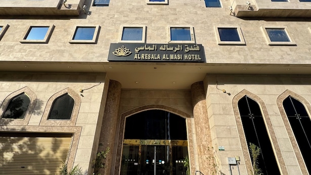 Exterior del hotel Al Resala Al Masi, con una entrada destacada, amplias ventanas y un cielo despejado.
