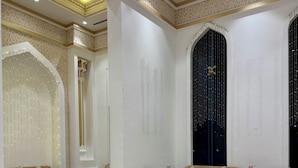 Un vestíbulo amplio con piso a cuadros, varios sofás y un techo decorativo con diseños geométricos.