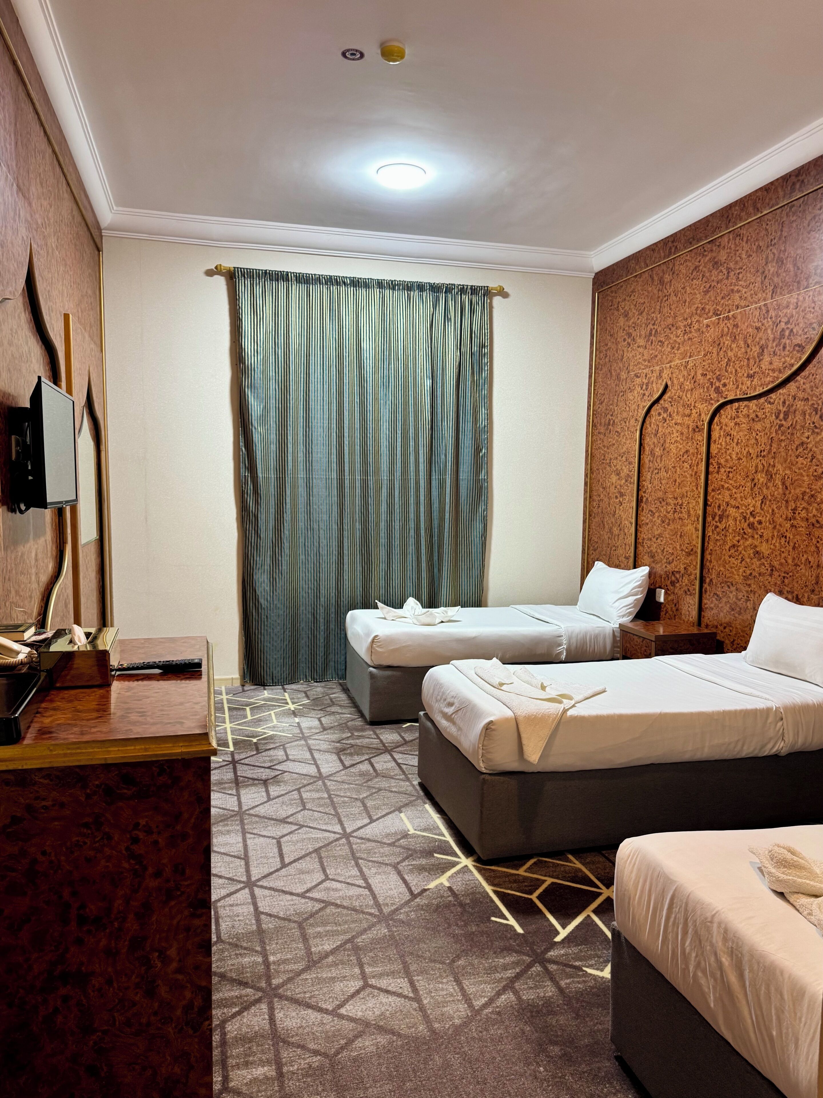 Habitación de hotel con dos camas, un escritorio, un teléfono y un televisor montado en la pared.
