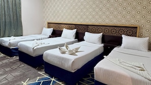 Una habitación de hotel con tres camas, un papel tapiz estampado y una alfombra geométrica.