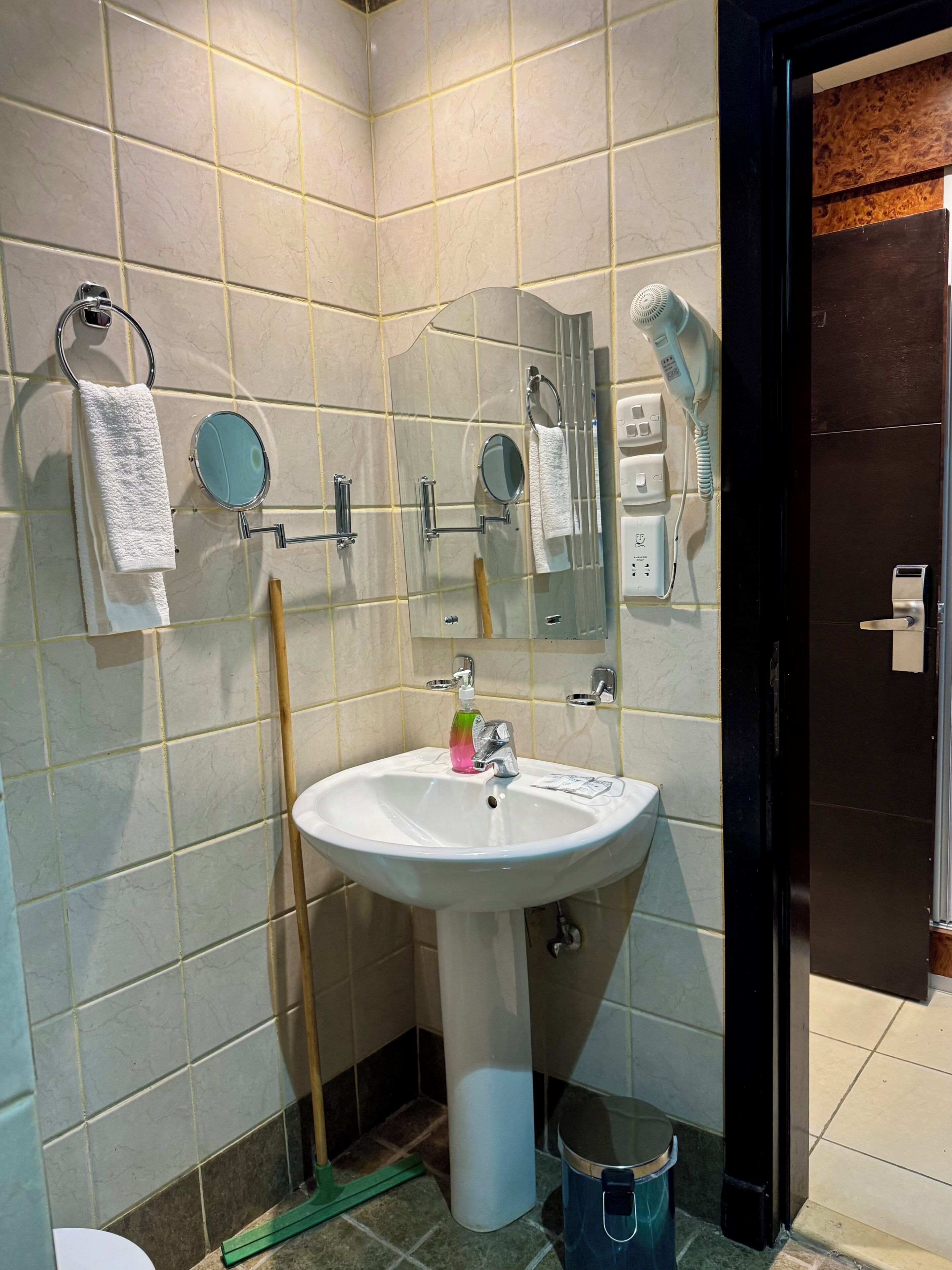 A bathroom with a sink, mirror, towel rack, and a hairdryer.