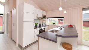 Moderni keittiö, jossa on valkoiset kaapit, mikroaaltouuni ja kahvinkeitin.