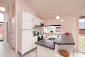 A modern kitchen with white cabinets, a microwave, and a coffee maker. - Küstenfamilienchalet mit Sauna (Großenbrode)
