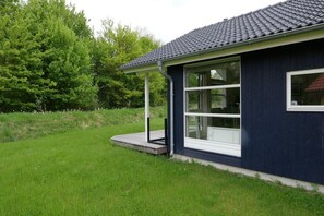 Ein eingeschossiges Gebäude mit dunkler Fassade, einer überdachten Veranda und einem großen Fenster.