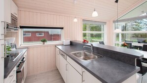 Una cocina moderna con una isla grande, electrodomésticos de acero inoxidable y una ventana con vista a un edificio rojo.