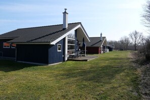 A residential property with a covered outdoor seating area and a separate building with a chimney. - Chalet im skandinavischen Stil für 6 Personen (Großenbrode)