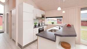 A modern kitchen with white cabinets, a microwave, and a coffee maker. - Chalet im skandinavischen Stil für 6 Personen (Großenbrode)
