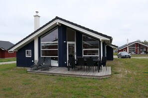 A single-story house with a covered porch, large windows, and a car parked outside. - Haus mit Spa und Whirlpool (Großenbrode)