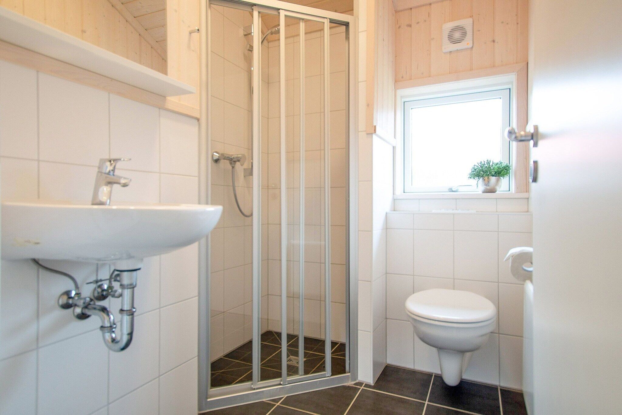 Et badeværelse med brusekabine, håndvask og toilet.