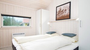 Quarto com duas camas, uma janela, um radiador e um quadro na parede.