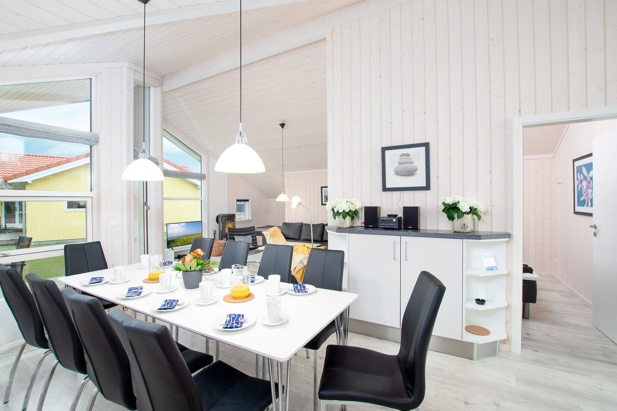 Een moderne eetruimte met een witte tafel voor vier personen, zwarte stoelen en hanglampen.