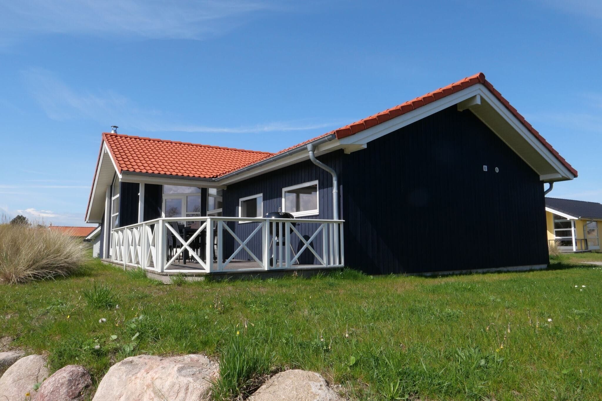 Een twee verdiepingen tellend huis met een dak van rode tegels, een balkon met witte leuningen, en een donkere buitenmuur.