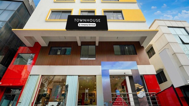 Um edifício de vários andares com uma placa que diz 'TOWNHOUSE Company-Serviced'.