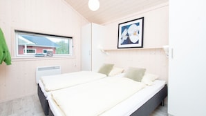 Ein Schlafzimmer mit Bett, Fenster, Heizkörper und einem Bild an der Wand.