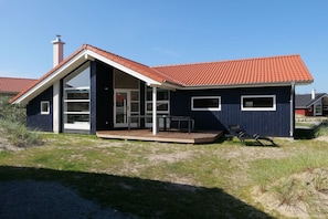 A modern house with a red-tiled roof, large windows, and a wooden deck. - Familienlodge für 10 Personen mit Sauna (Großenbrode)