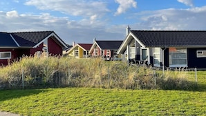 En rad envåningshus med sadeltak, omgivna av en gräsyta och ett staket.