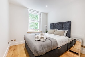 A modern bedroom with a large bed, a window, and a bedside table. - Spacious 2BR 2BA Fitzrovia close to Bloomsbury (London)