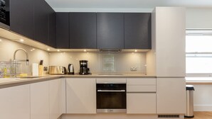 Eine moderne Küche mit Geschirrspüler, Backofen und Kaffeemaschine.