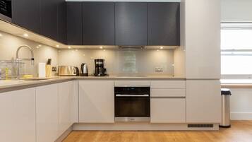 A modern kitchen with a dishwasher, oven, and coffee maker.