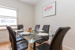 A dining area with a glass table and black leather chairs, a fruit plate, and a framed artwork on the wall. - Spacious 2BR 2BA Fitzrovia close to Bloomsbury (London)