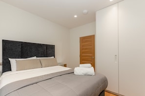 A bedroom with a bed, a wardrobe, and a door. - Spacious 2BR 2BA Fitzrovia close to Bloomsbury (London)