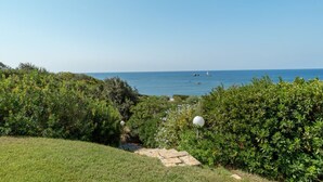 A coastal landscape with a grassy area, dense shrubbery, and a clear view of the sea. - Villa Marina, an authentic Mediterranean home overlooking the sea of Villasimius (VILLASIMIUS)