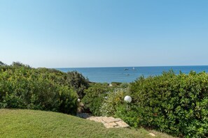 A coastal landscape with a grassy area, dense shrubbery, and a clear view of the sea. - Villa Marina, an authentic Mediterranean home overlooking the sea of Villasimius (VILLASIMIUS)