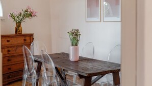 A dining area with a wooden table, clear chairs, a vase with flowers, and a wooden cabinet. - Villa Marina, an authentic Mediterranean home overlooking the sea of Villasimius (VILLASIMIUS)