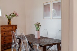 A dining area with a wooden table, clear chairs, a vase with flowers, and a wooden cabinet. - Villa Marina, an authentic Mediterranean home overlooking the sea of Villasimius (VILLASIMIUS)