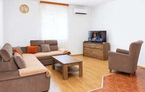 Ein Wohnzimmer mit Sofa, Sessel, Couchtisch und Fernseher auf einem Holzschrank.