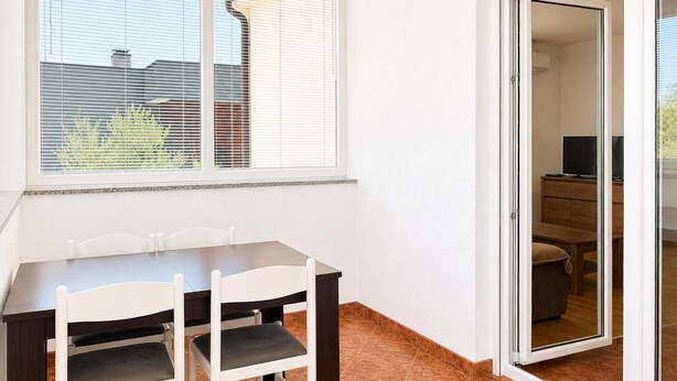 A dining area with a table and chairs, a sliding glass door leading to a living space, and a window with blinds. - 3 bedroom stunning apartment in Pula (Pula)