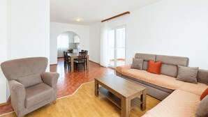 A living room with a sofa, armchair, and a wooden coffee table. - 3 bedroom stunning apartment in Pula (Pula)