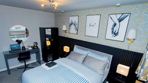 Una habitación de hotel con cama, escritorio y espejo.