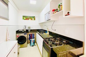 Cocina funcional con lavadora, cocina a gas y microondas.