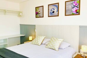 Ein Hotelzimmer mit einem Bett, Nachttischen, Ablageflächen und drei gerahmten Kunstwerken.
