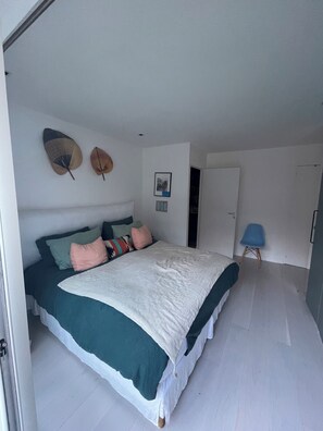 A bedroom with a bed, pillows, a wall-mounted hat, and a door. - The Place to Be: Monticelli Square (Marseille)