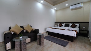Habitación de hotel con cama, sofá, una mesita y aire acondicionado.