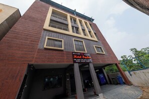 Un hotel con letrero, entrada con portón y balcón visible.