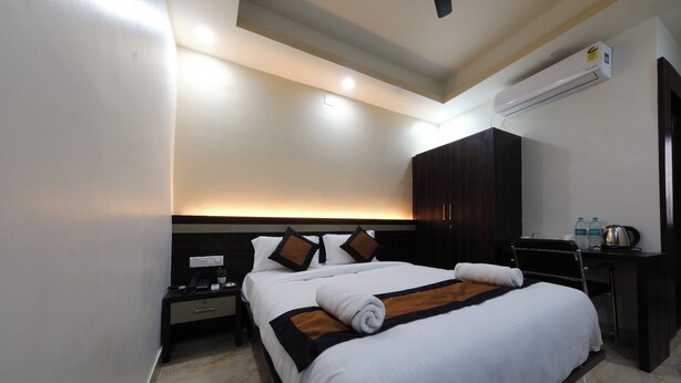 A hotel room with a large bed, a bedside table with a lamp, a wardrobe, and an air conditioning unit. - Hotel Anchor (Ranchi)