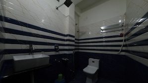 Un baño con lavamanos blanco, inodoro y zona de ducha.