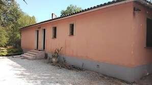 A single-story building with a flat roof, a small porch, and a gravel driveway. - House in the Provençal countryside (Le Thoronet)