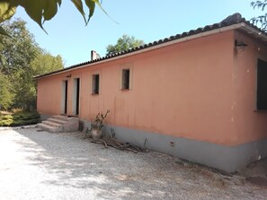 A single-story building with a flat roof, a small porch, and a gravel driveway. - House in the Provençal countryside (Le Thoronet)