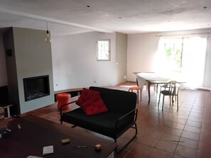 Ein Wohnzimmer mit Sofa, Couchtisch, Kamin und einem Essbereich mit Tisch und Stühlen.