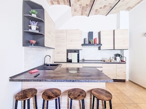 A modern kitchen with a central island, bar stools, and a built-in oven. - Majella Living by Interhome (Caramanico Terme)