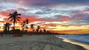 A beach with palm trees and a sunset. - Deluxe Apartment with Sea View & Pool Cumbuco (Praia de Cumbuco)