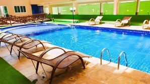 A swimming pool with lounge chairs and a tiled deck. - Deluxe Apartment with Sea View & Pool Cumbuco (Praia de Cumbuco)