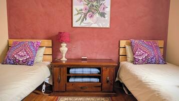 A bedroom with two beds, a nightstand, a lamp, and a floral artwork on the wall.